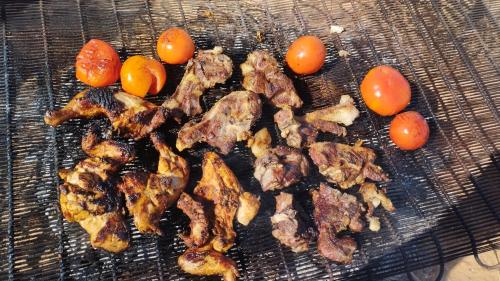 a grill with some meat and tomatoes on it at Wadi rum sand Delight camp in Wadi Rum