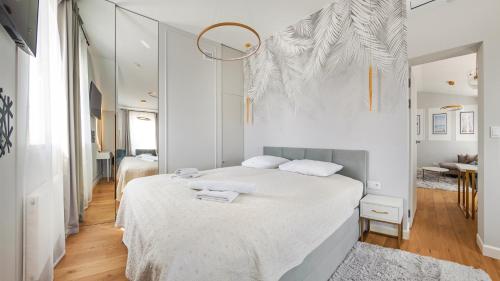 een witte slaapkamer met een groot bed met witte lakens bij Apartamenty Sun & Snow Rozewska Natura Park in Jastrzębia Góra