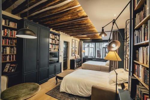 a bedroom with two beds and bookshelves at Quartiers Enfants Rouges,Bretagne - Appartement d'architecte 4P in Paris