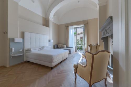 a white bedroom with a bed and a chair at Hotel Ariele in Florence