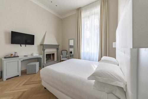 a white bedroom with a bed and a fireplace at Hotel Ariele in Florence