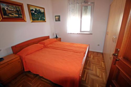 a bedroom with an orange bed and a window at Apartment Branka in Premantura
