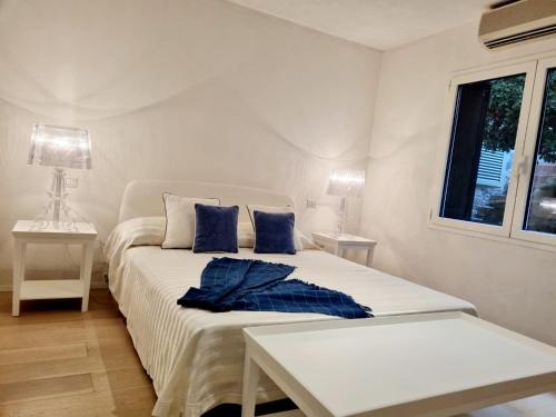 a white bedroom with a bed with blue pillows at House Casbah Porto Rotondo in Porto Rotondo