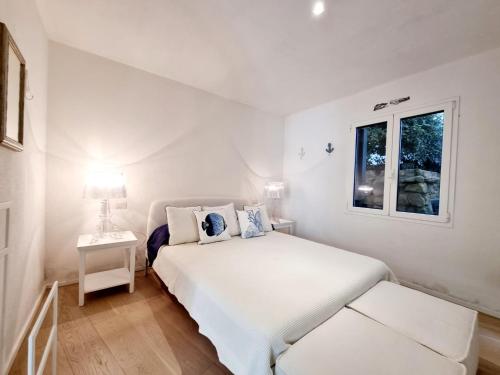 a white bedroom with a bed and a window at House Casbah Porto Rotondo in Porto Rotondo
