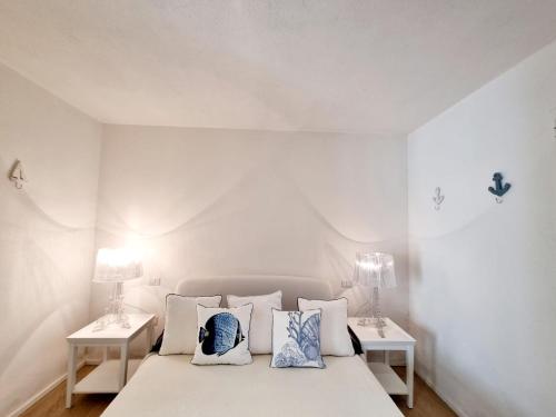 a white bedroom with a bed with two tables at House Casbah Porto Rotondo in Porto Rotondo