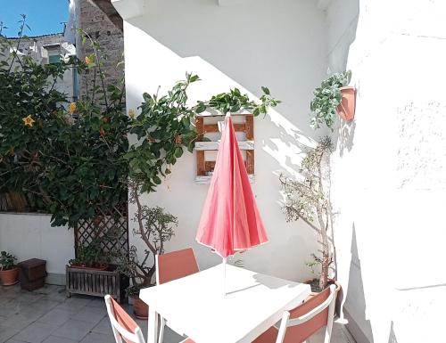 een patio met een tafel en een rode parasol bij Dietro il massimo in Palermo