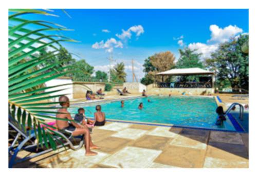 a group of people sitting around a swimming pool at Rozala Motel in Bondo