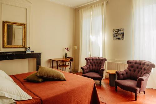 a bedroom with a bed and two chairs and a mirror at La Maison de Gruissan in Gruissan