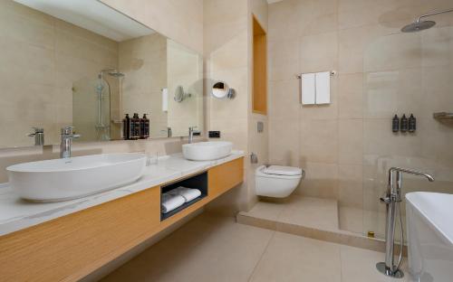 a white bathroom with a sink and a toilet at Mercure Tashkent in Tashkent