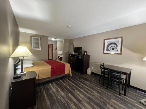 a hotel room with a bed and a desk and chair at Rodeway Inn in Holdrege