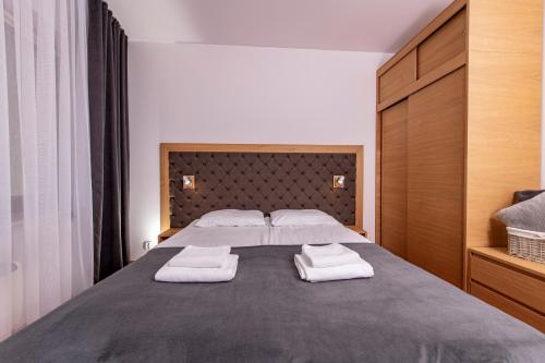 ein Schlafzimmer mit einem großen Bett und zwei Handtüchern in der Unterkunft Prywatny Apartament 413 w Arka Medical Spa przy plaży in Kołobrzeg