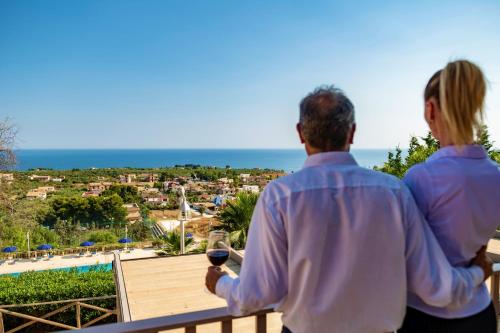 a man and woman standing on a balcony with a glass of wine at Aparthotel Isabella in Sciacca