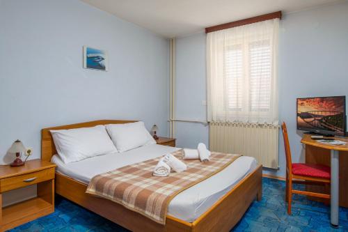 Dormitorio con cama, escritorio y TV en HOTEL KRALJEVICA, en Kraljevica