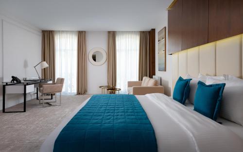 a hotel room with a large bed and a desk at Mercure Tashkent in Tashkent