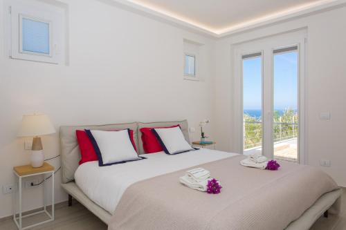 a white bedroom with two beds and a window at Villa Annalisa by PosarelliVillas in Pizzolungo