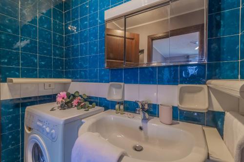 een blauwe betegelde badkamer met een wastafel en een wasmachine bij Ca' Maria Peonie by Wonderful Italy in Bellagio