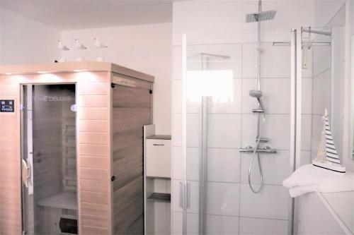La salle de bains est pourvue d'une douche avec une porte en verre. dans l'établissement 47 2 M Seestern, à Wangerland