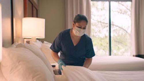 a woman in a mask making a bed at Rodeway Inn in Holdrege