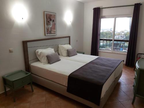 Un dormitorio con una cama grande y una ventana en Clube Alvor Ria - Waterfront luxury apartments with stunning views, en Alvor