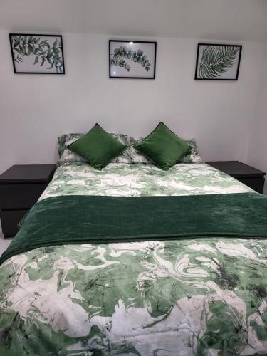 a bedroom with a bed with a green comforter at Fancy Basement Flat B in London