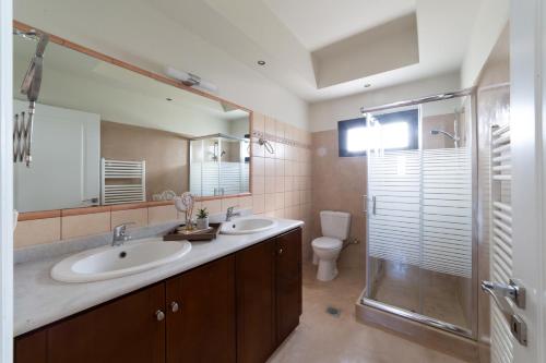 a bathroom with two sinks and a shower and a toilet at Villa Louke in Lixouri