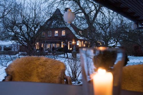 a candle in front of a house in the snow at Landgasthof Kasch - Hotel und Restaurant in Malente