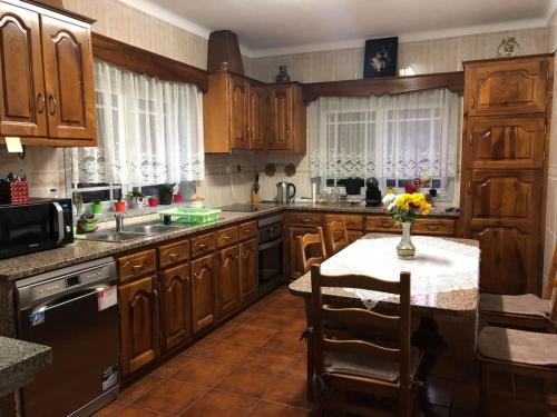 a kitchen with wooden cabinets and a table with a vase of flowers at Quinta da Fervença, private river place to relax.. in Sernancelhe