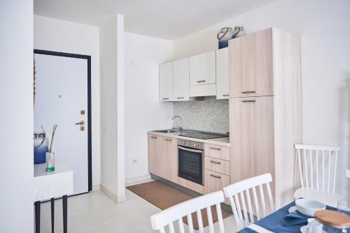 uma cozinha com armários brancos e uma mesa com cadeiras em Seabay em Golfo Aranci