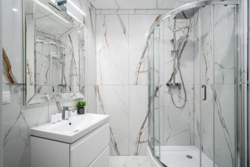 uma casa de banho branca com um lavatório e um chuveiro em Warsaw Apartments Bliska Wola em Varsóvia