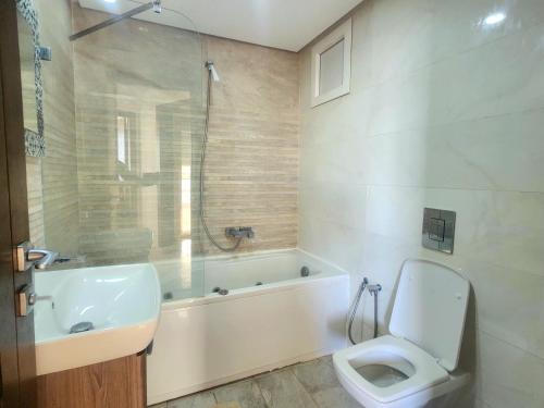 a bathroom with a toilet and a tub and a sink at Accueillant S+1 jardin de carthage in Tunis