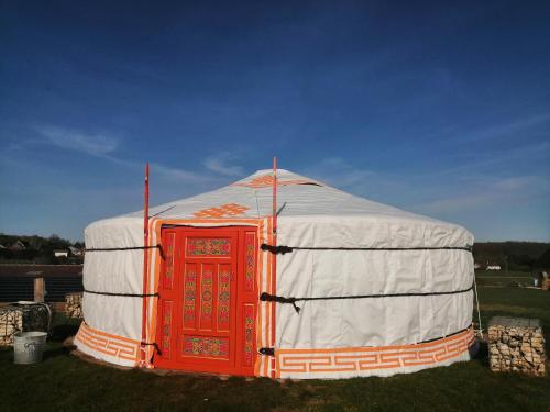 uma tenda laranja e branca com uma porta vermelha em La ferme autour du Grain em Bouglainval