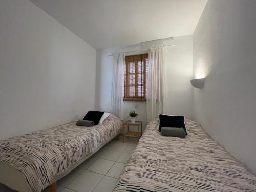 a bedroom with two beds and a window at Bungalow Einstein in Maspalomas