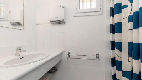 La salle de bains blanche est pourvue d'un lavabo et d'une fenêtre. dans l'établissement Perles du Soleil- 50- Maison mezzanine- 6 pers, au Cap d'Agde