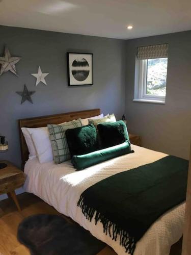 1 dormitorio con 1 cama con almohadas verdes y estrellas en la pared en Cute studio cottage. Wood burner. Amazing views, en Longhope