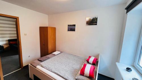 a small bedroom with a bed with red and white pillows at Ośrodek Wypoczynkowy KROPELKA in Dębowa Kłoda