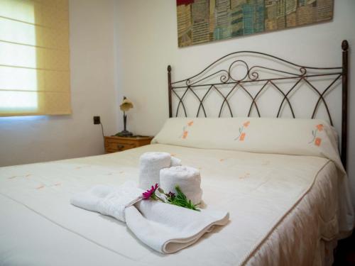 a bedroom with towels and flowers on a bed at Casa La Ronda. in Jódar