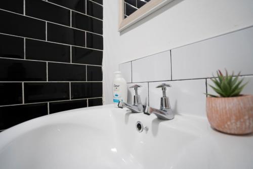a white sink in a bathroom with black tiles at 2 Bed-Town Centre-Free Parking in Old Walker