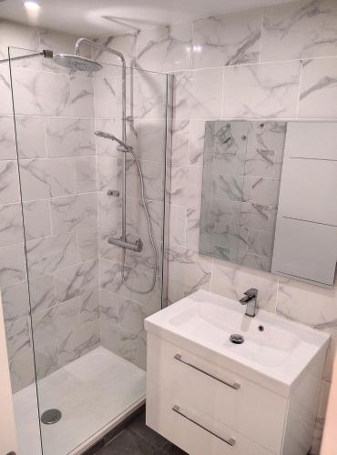 une salle de bain blanche avec une douche et un lavabo dans l'établissement Résidence le Serra, à Juan-les-Pins