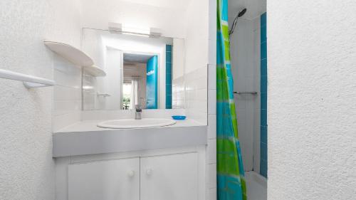 une salle de bain blanche avec un lavabo et une douche dans l'établissement Cristallines- 89- Maison mezzanine- 6 pers, au Cap d'Agde