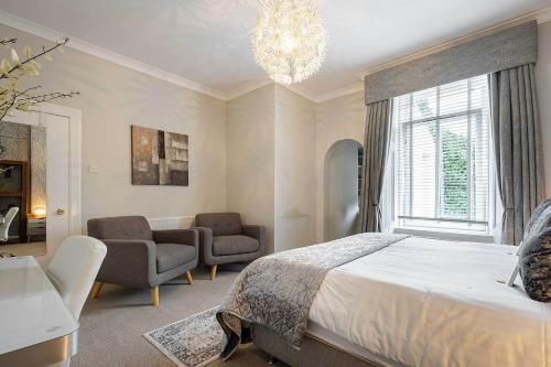 a bedroom with a bed and chairs and a chandelier at Carmel Apartments in Falkirk