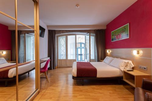 a hotel room with two beds and a red wall at Casual Arriaga in Bilbao
