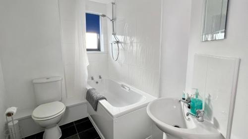 a white bathroom with a toilet and a tub and a sink at Cross Court, Stafford by BELL Apartments in Stafford