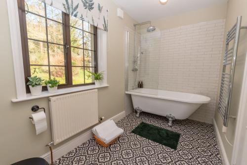 een witte badkamer met een bad en een raam bij Nutsford House in Dulverton