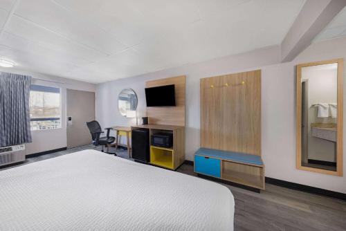 a hotel room with a bed and a desk and a table at Days Inn by Wyndham Fredericksburg North in Fredericksburg
