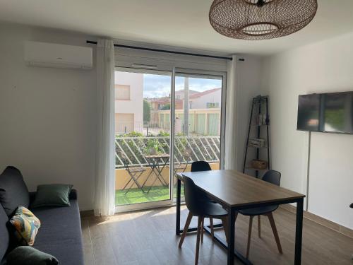 ein Wohnzimmer mit einem Tisch und Blick auf einen Balkon in der Unterkunft Petit cocon à Sanary-sur-Mer in Sanary-sur-Mer