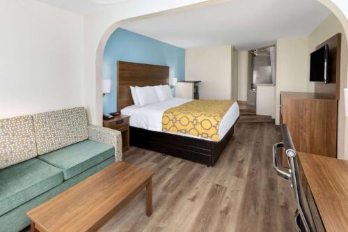 a hotel room with a bed and a couch at Baymont by Wyndham Biloxi - Ocean Springs in Biloxi