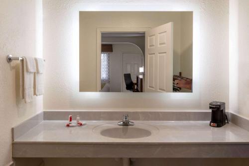 a bathroom with a sink and a mirror at Baymont by Wyndham Biloxi - Ocean Springs in Biloxi