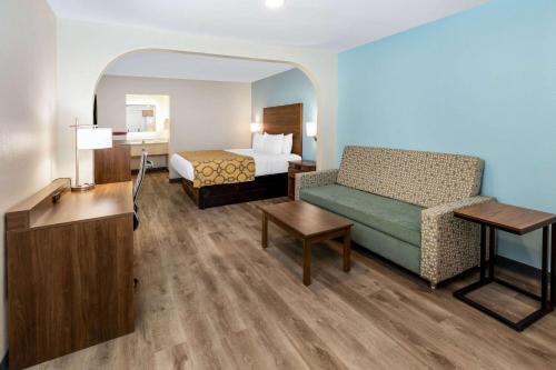 a hotel room with a bed and a couch at Baymont by Wyndham Biloxi - Ocean Springs in Biloxi