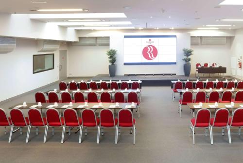a conference room with red chairs and a screen at Ramada Plaza by Wyndham Milano in Milan