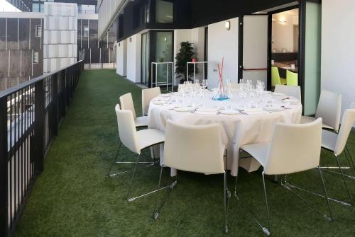 a long table with white chairs in a room at Ramada Plaza by Wyndham Milano in Milan